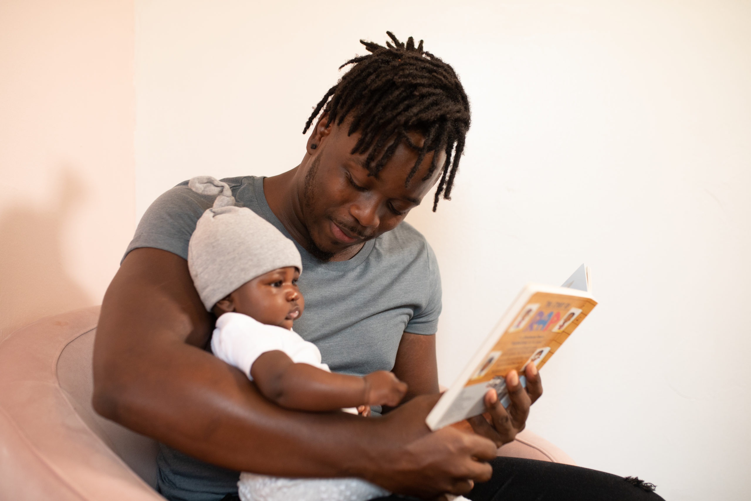 Man in gray shirt holding baby in white onesie